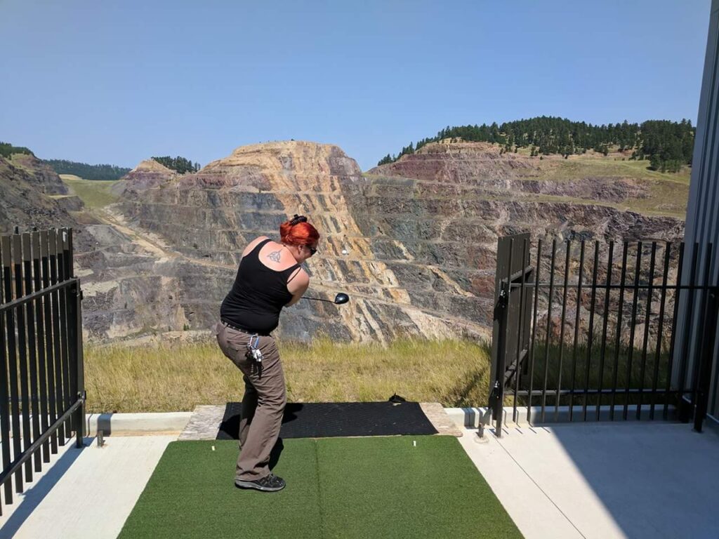 Hitting a golf ball into the abandoned mine pit at the Sanford Lab Homestake visitor's center in Lead, South Dakota.