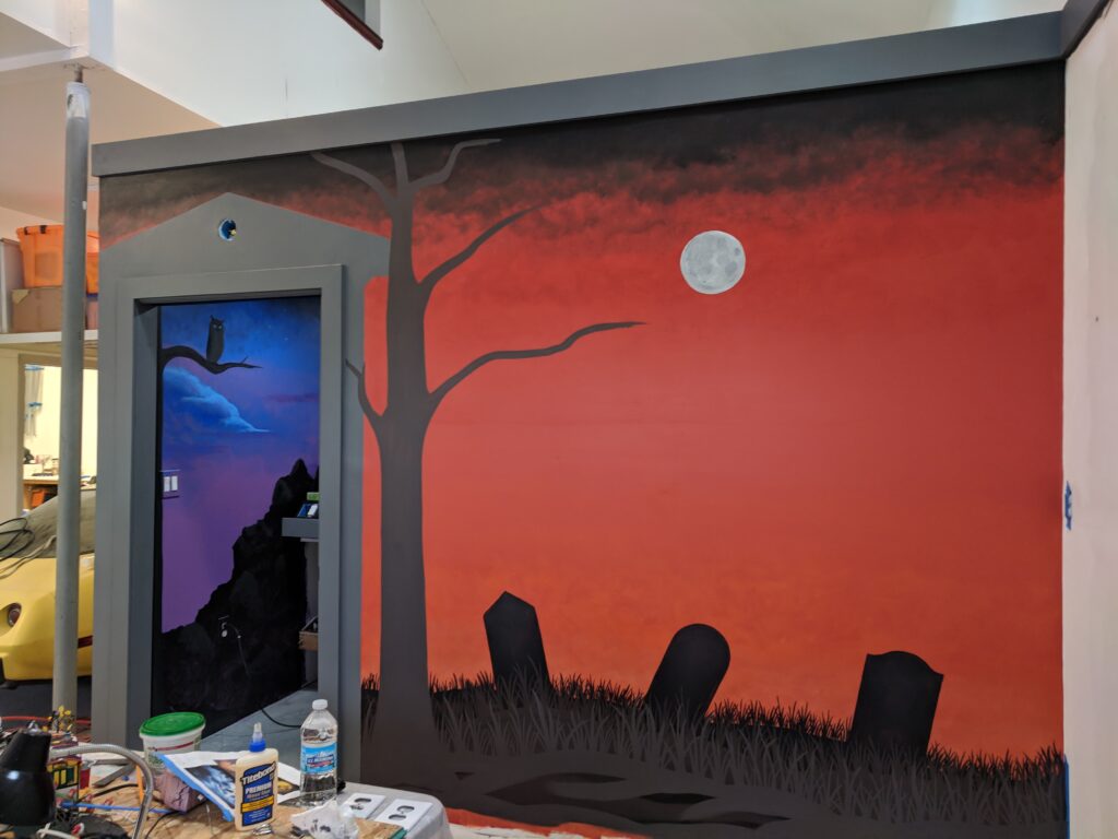 Halloween mural, with the moon, tree, and cemetery in progress.